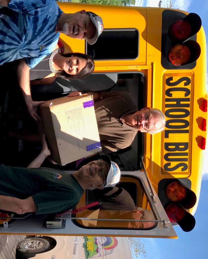 A group of people standing in front of a yellow school bus.