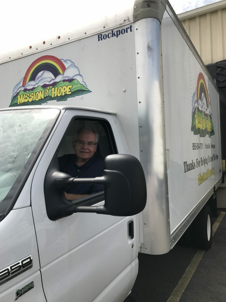 A man sitting in the driver's seat of a moving truck.