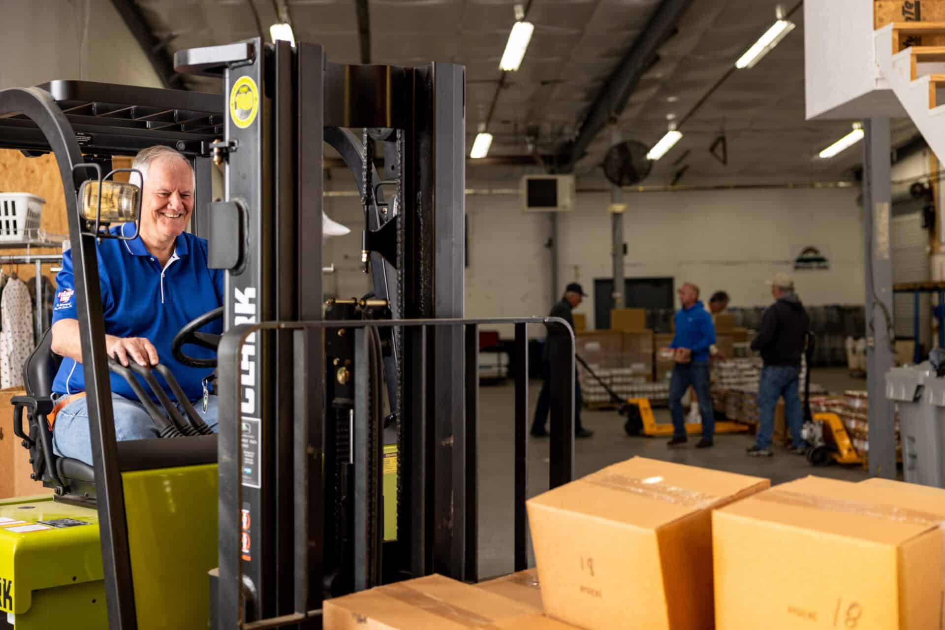 A man on a forklift. Volunteers
