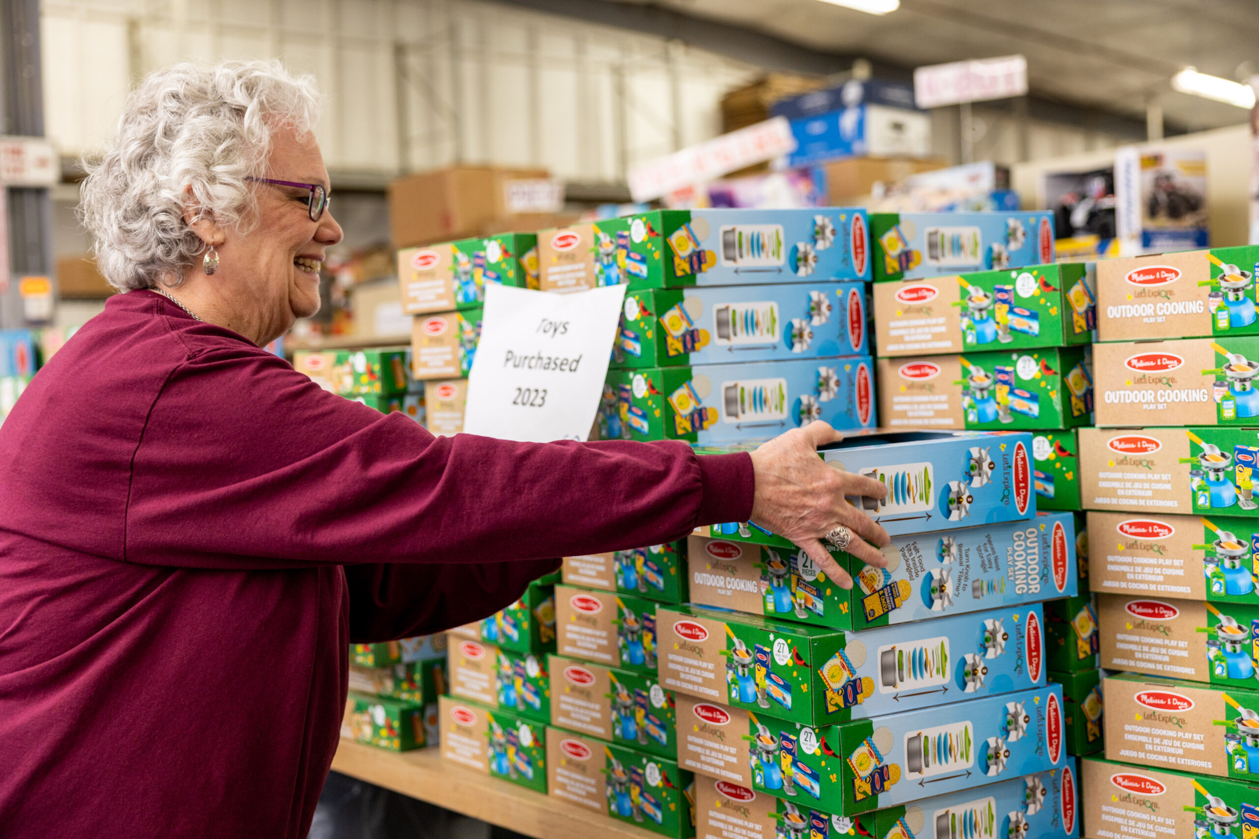 A woman picking up boxes of cereal at a warehouse.