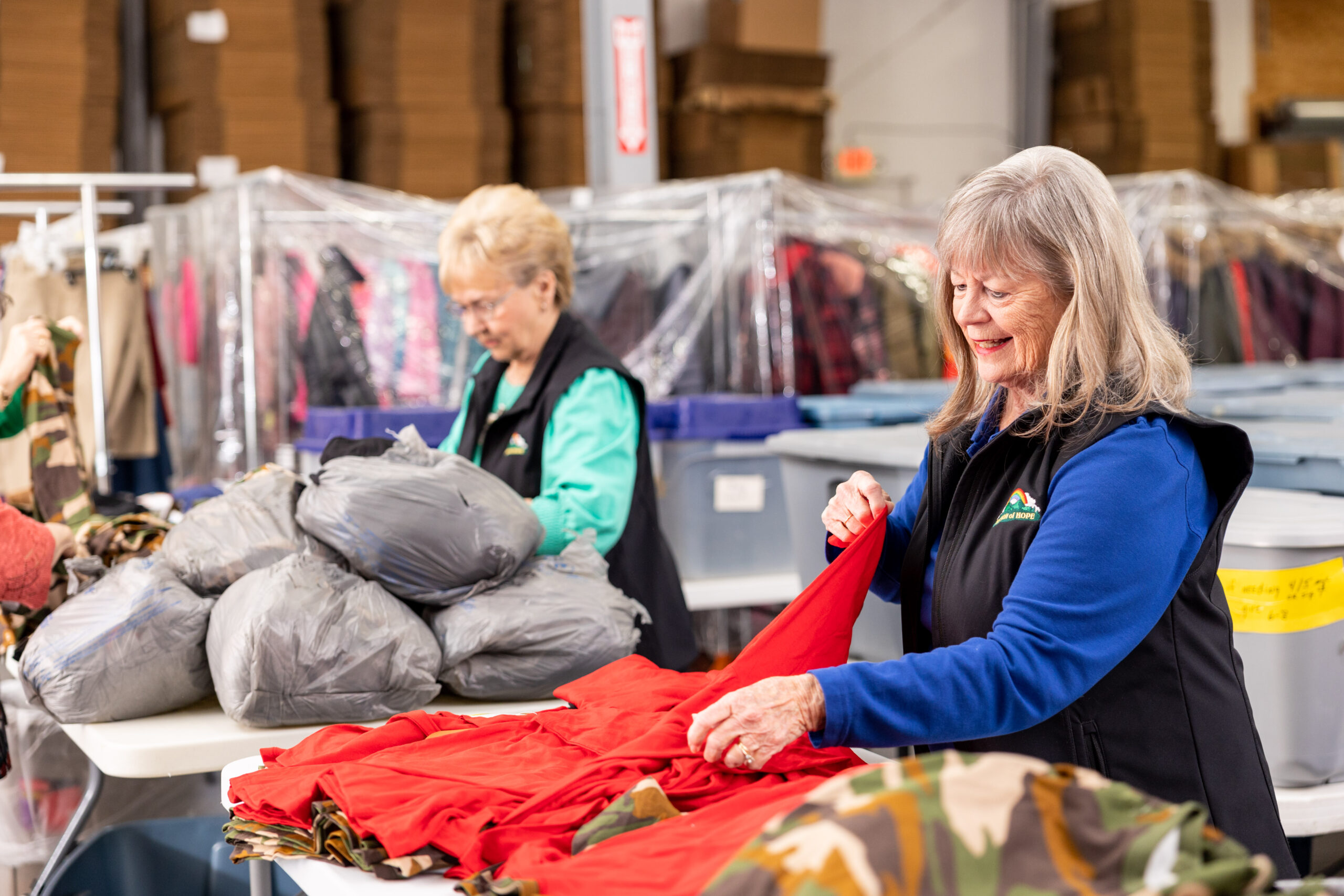 Two women sorting clothes in a warehouse.