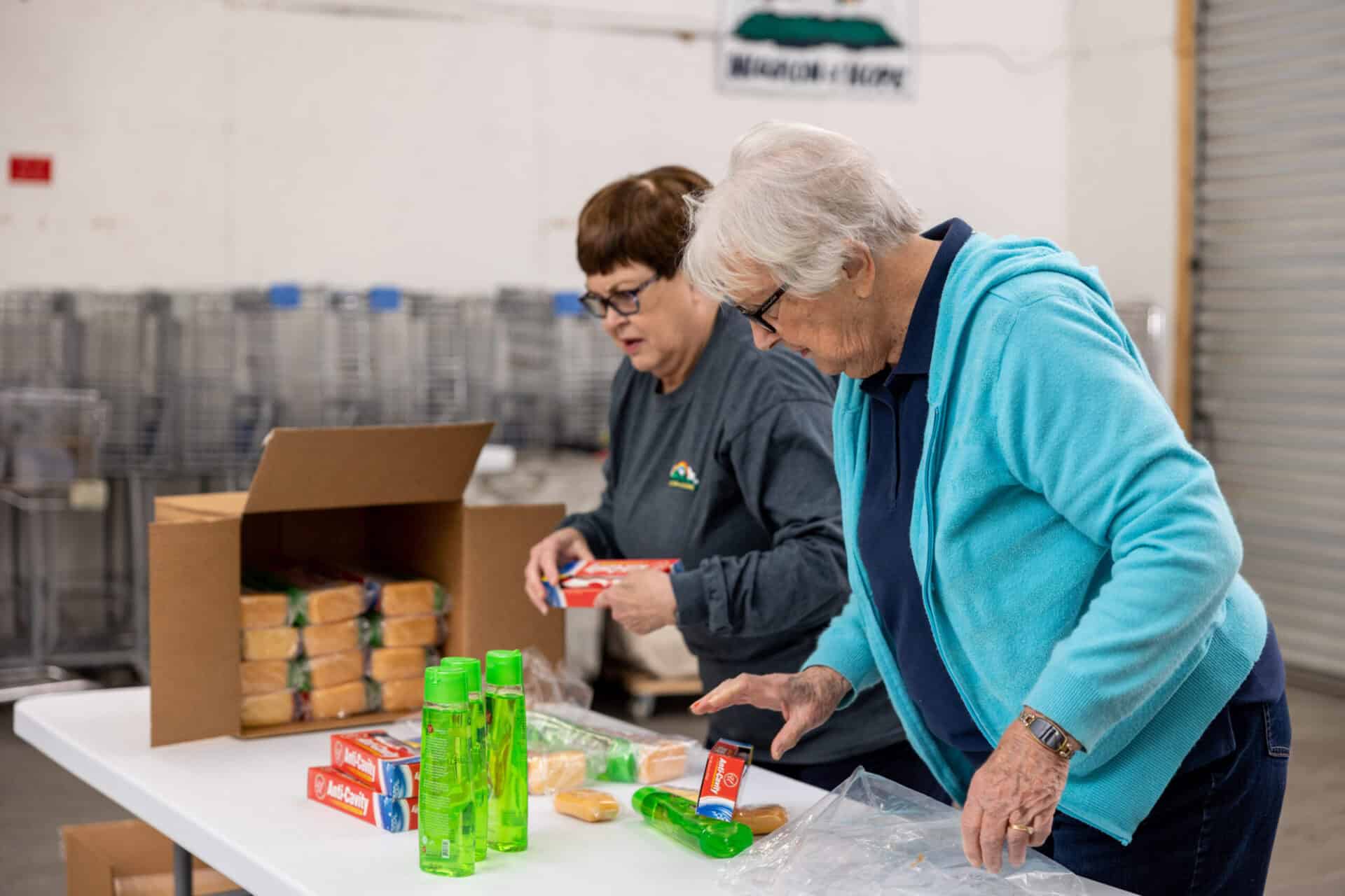 Two women are preparing food in a warehouse.