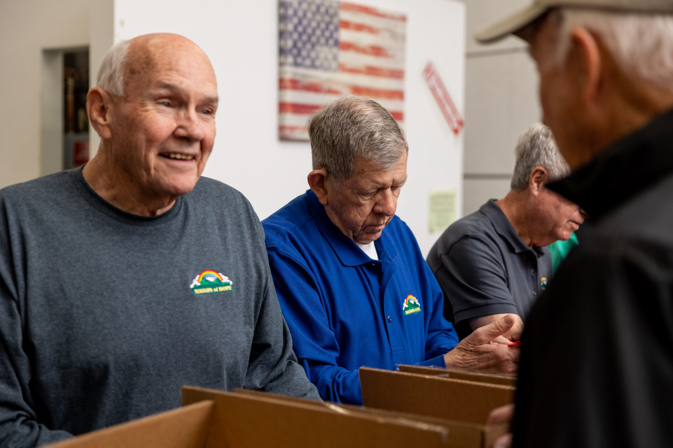 A group of older men standing in a warehouse.