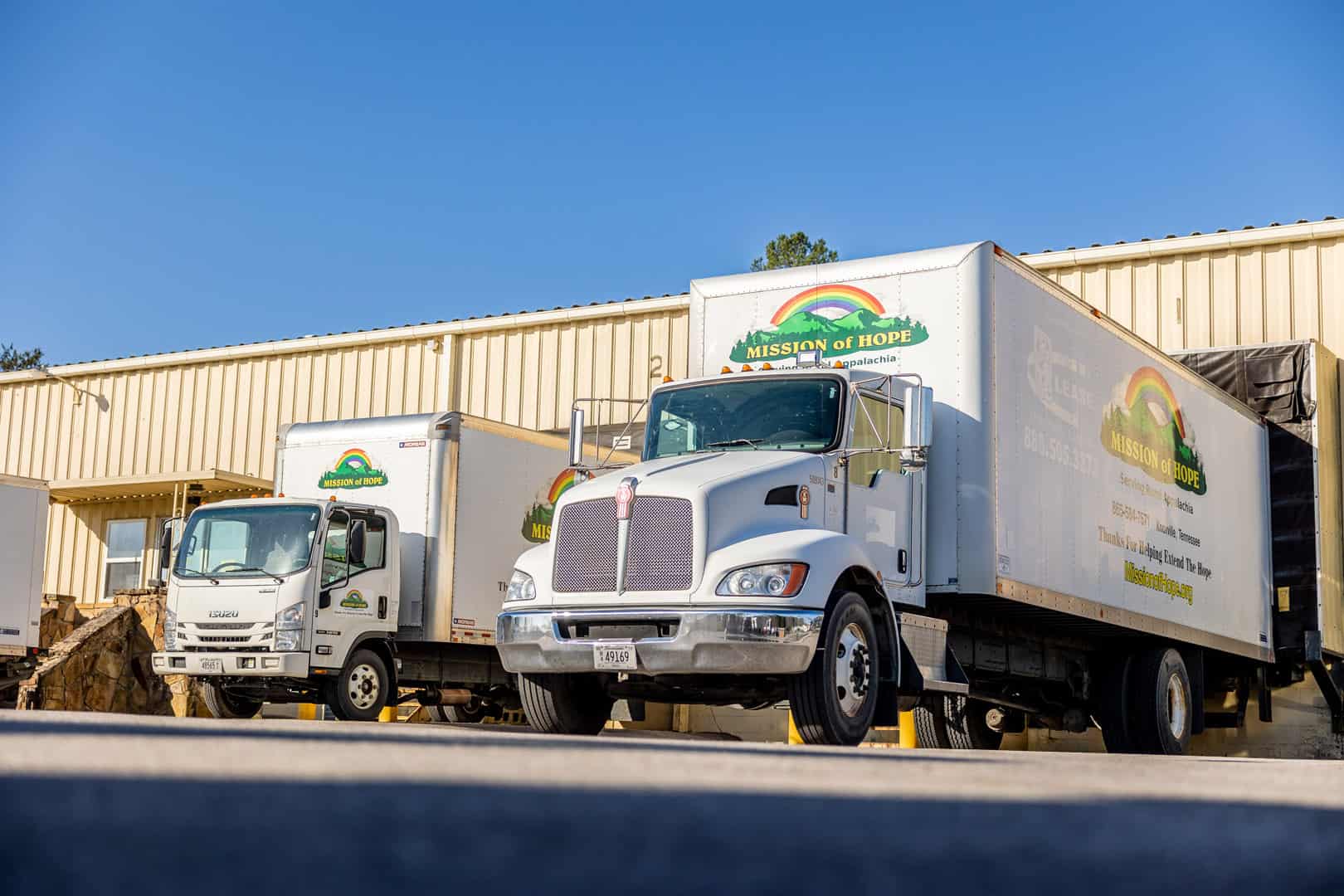 Two white trucks parked in front of a building.