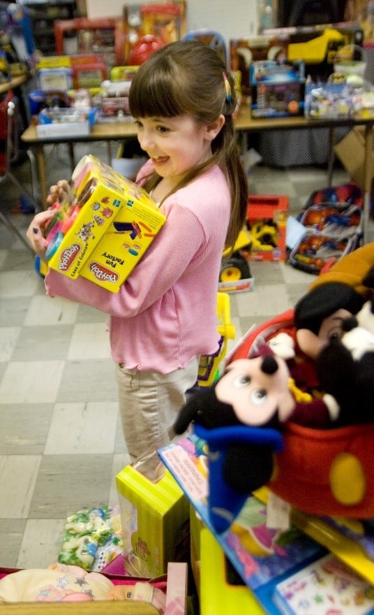 A young girl standing in a room full of stuffed animals.