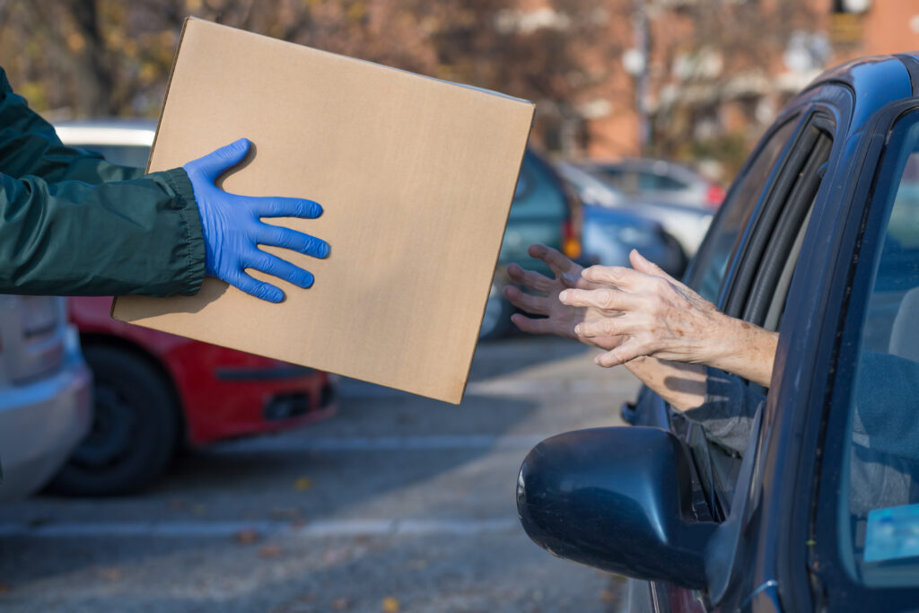 A man is handing a box to a woman in a car.